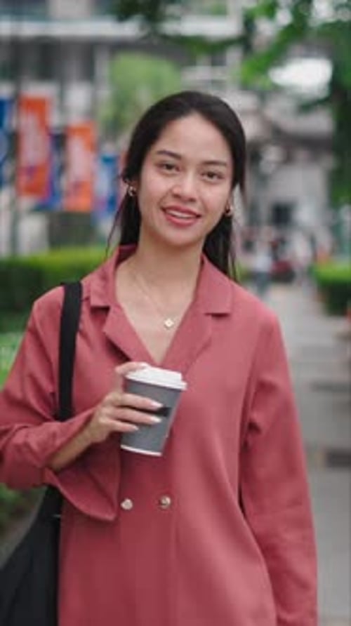 Young Asian Businesswoman Walking and Holding a Coffee on a City Street