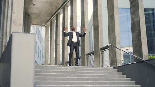 Happy excited african american businessman celebrating victory success outside in front of office