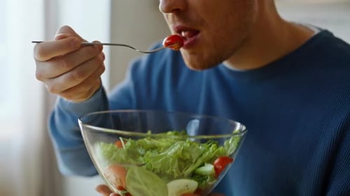 Man Enjoys Eating a Fresh Salad Indoors