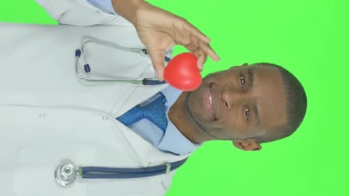 Vertical Video of African Doctor Showing Red Heart on Green Background