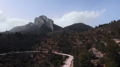 Empty asphalt winding mountain road with huge rocky mountain cliff on background
