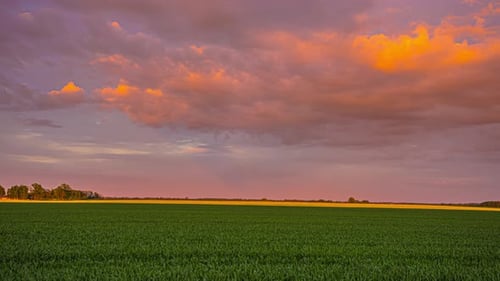 Time lapse shot of idyllic agriultural field and moving clouds on colorful sky after sunset - 5K foo