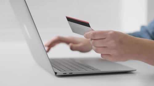 Person Holding a Credit Card While Typing on a Laptop Making an Online Payment or Shopping