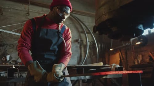African American Blacksmith Using Hydraulic Forging Press in Workshop