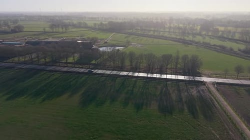 Aerial landscape of green European farmlands at sunrise Long tree shadows stretch across lush fields