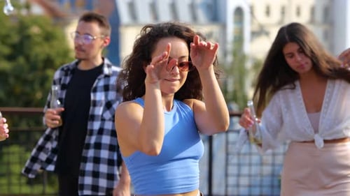 Vista de perto de uma jovem morena se divertindo com amigos na Sunset Disco, movendo-se ritmicamente para