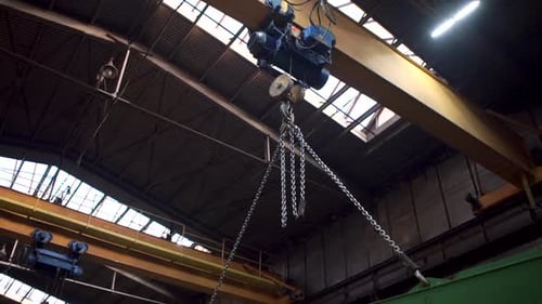 Industrial Crane Lifting Green Metal Beam in Factory