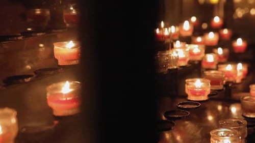 the camera moves around candles burning in the temple. tongues of flame fluctuate from the movement
