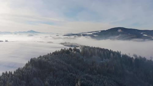 Unglaublicher Drohnenflug über verschneite Winterwaldlandschaft mit Wolken und Bergen