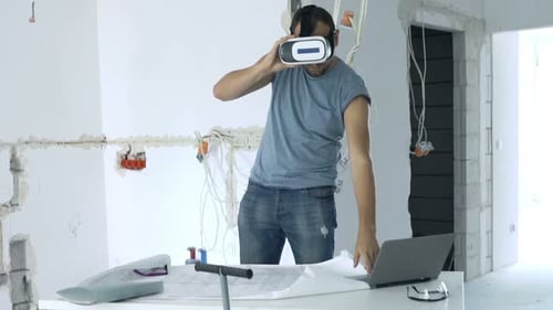 Jeune homme avec des lunettes VR visualisant un nouveau projet de maison sur un ordinateur portable