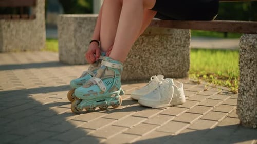 Woman Puts on Roller Blades in Park