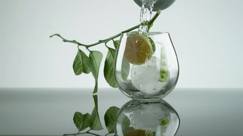 Pouring Water into Glass with Ice and Lime