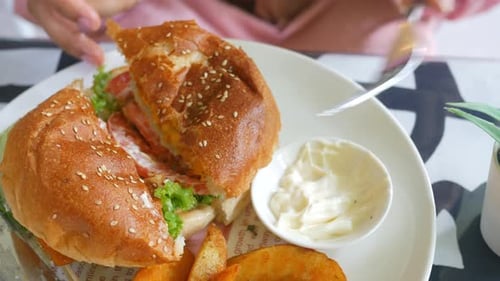 Hand Holding Beef Burger on Table Close Up