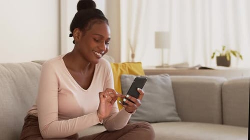 Young African American Woman Chatting with Friends Via Internet Texting on Smartphone Tracking Shot