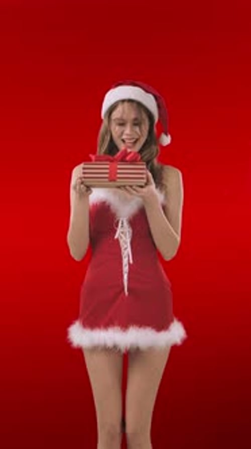 Woman in Santa Outfit Holding Christmas Gift