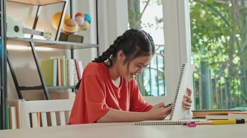 Chica asiática que usa el teléfono furtivamente en la escuela