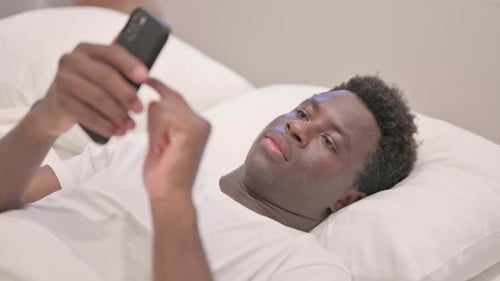 Adult Using Phone While Lying in Bed