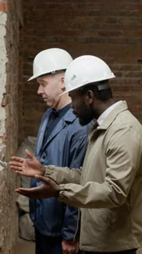 Construction Workers Having Discussion by Window on Site