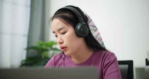 Woman at Laptop with Headphones in Online Meeting