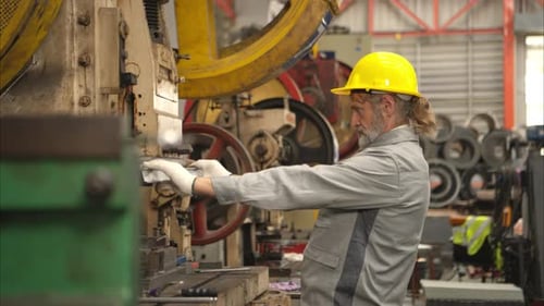 Senior experienced technician checking and maintenance a large machine in metal sheet factory