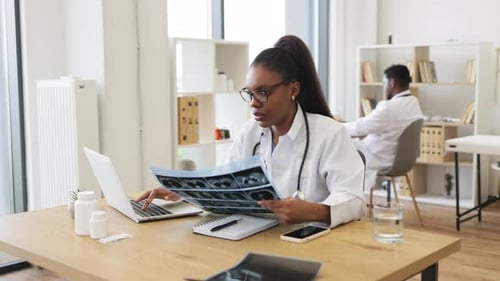 Female Doctor Reviews X-Ray in Bright Office