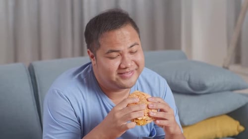 Man Enjoys Burger Comfortably at Home