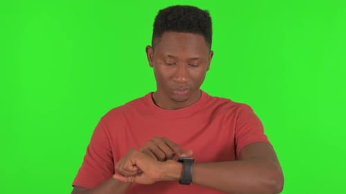 Young African Man using Smart Watch on Green Background