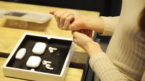 A Closeup of a Girl in a Sweater Chooses Bluetooth Headphones in a Store