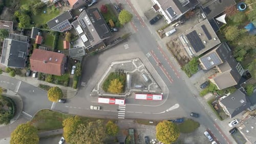 Top down aerial of people stepping out of bus at bus station - drone setting down