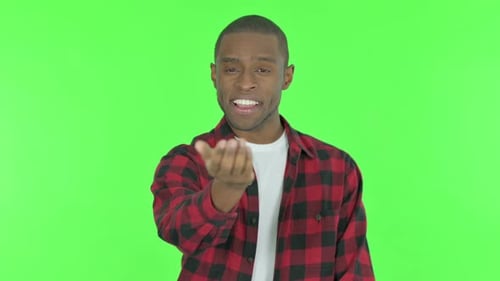 Pointing African Man Inviting on Green Background