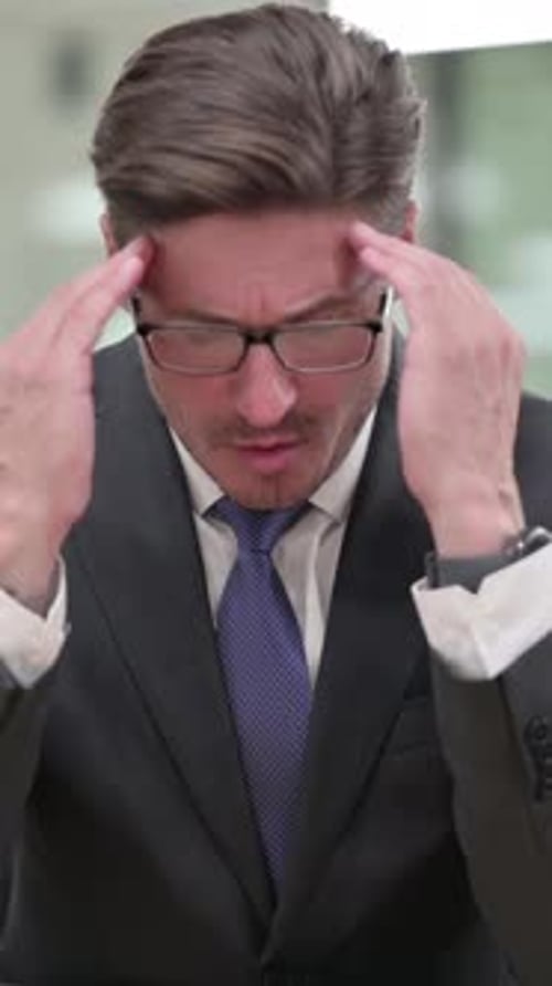 Businessman Massaging Temples in Office Showing Stress