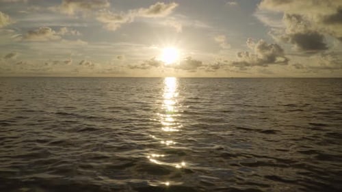 ocean sunrise with clouds and reflected sunbursts in water landscape