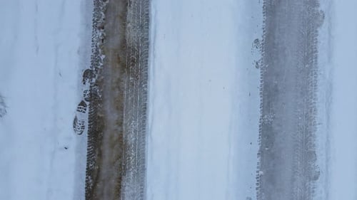 Top down tyre tracks on snow on a snow-covered road, slow motion regular back track