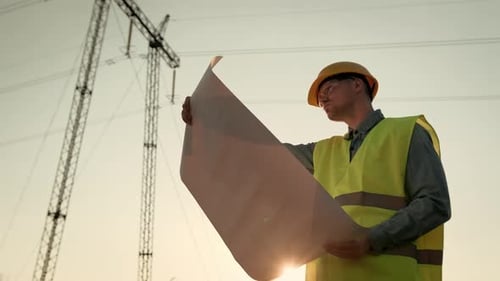Power Line Inspector Holding Technical Drawings During Electricity Inspection