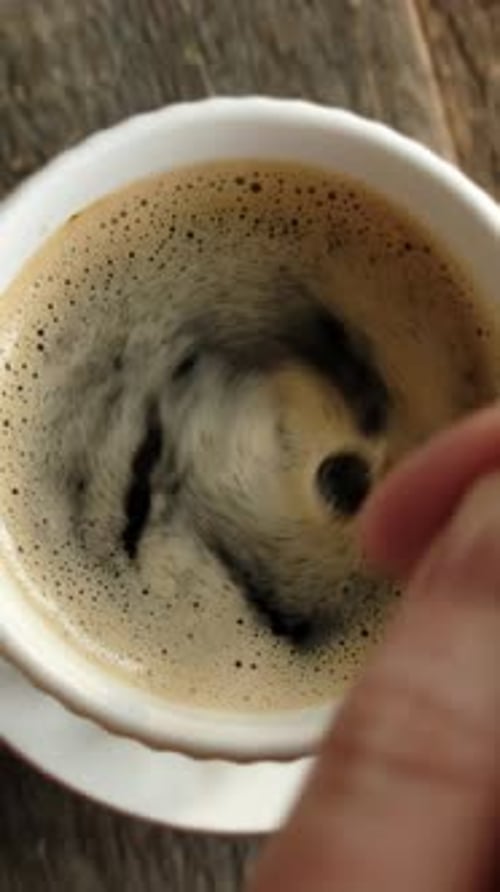 Vertical Video Hand Stirring Sugar in a Mug of Espresso Coffee