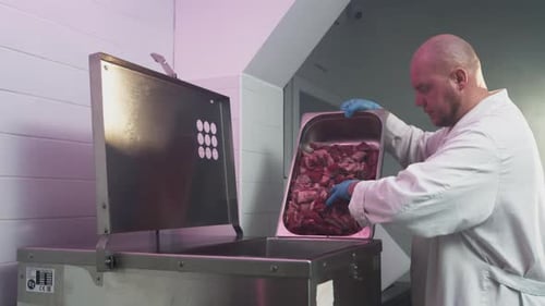 Man Worker in White Robe Empties Minced Meat From Large Metal Basin Processing of Production Ground