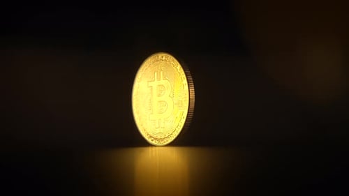 Une pièce Bitcoin brillamment illuminée mise en valeur sur un fond sombre