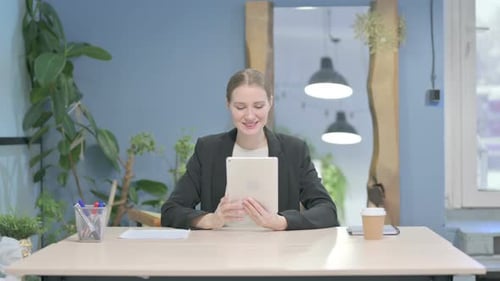 Woman Waving at Tablet Computer in Office