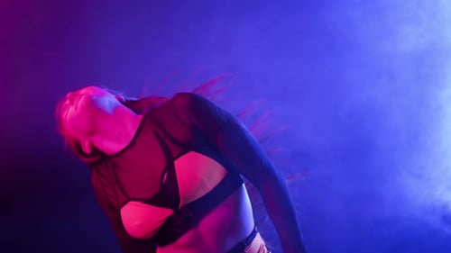Heiße Frau führt sexy lange Haarbewegungen durch und schüttelt den Kopf im Neonlicht auf der Bühne Verführerischer Privattanz