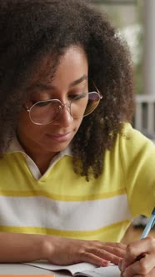 Focused Young Woman Writes in Notebook at Desk