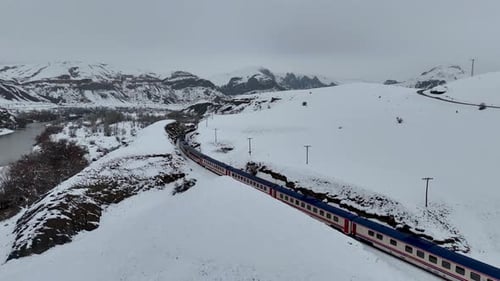 Personenzug fährt durch die verschneite Berglandschaft