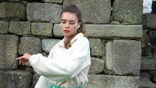 Brunette Woman Stretching Arms in Front of Wall