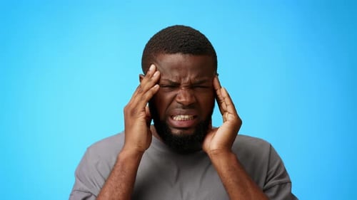 Man with Headache Rubbing Temples in Pain