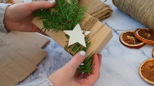 Woman Making Box with New Year's Gifts Wrapped in Craft Paper and Decorated with Fir Branch