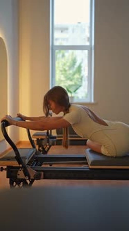 Woman Doing Pilates on Reformer Machine Indoors