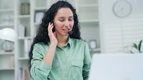 Young Adult Woman Speaking with Headset at Computer