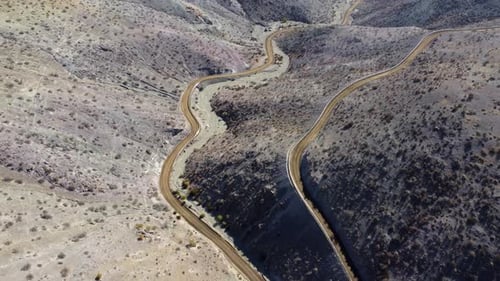 Unpaved road descends from rustic hills into narrow remote valley