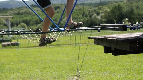 Closeup of a Little Boy's Feet on a Rope Road in an Amusement Park