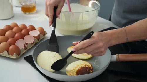 Femme retournant des crêpes à côté d'un coquetier. Gros plan au ralenti