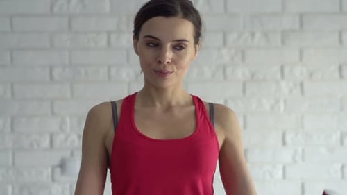 Woman Lifting Weights in Front of Brick Wall